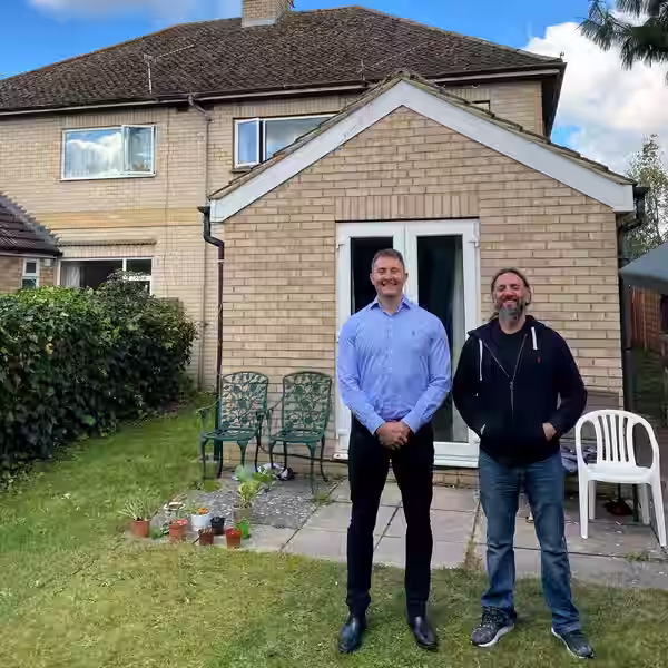 Rory and Dan standing in front of a house